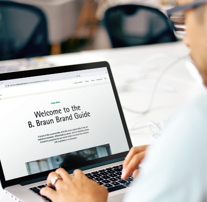 A man in a light blue shirt operating a laptop with the B. Braun website open.